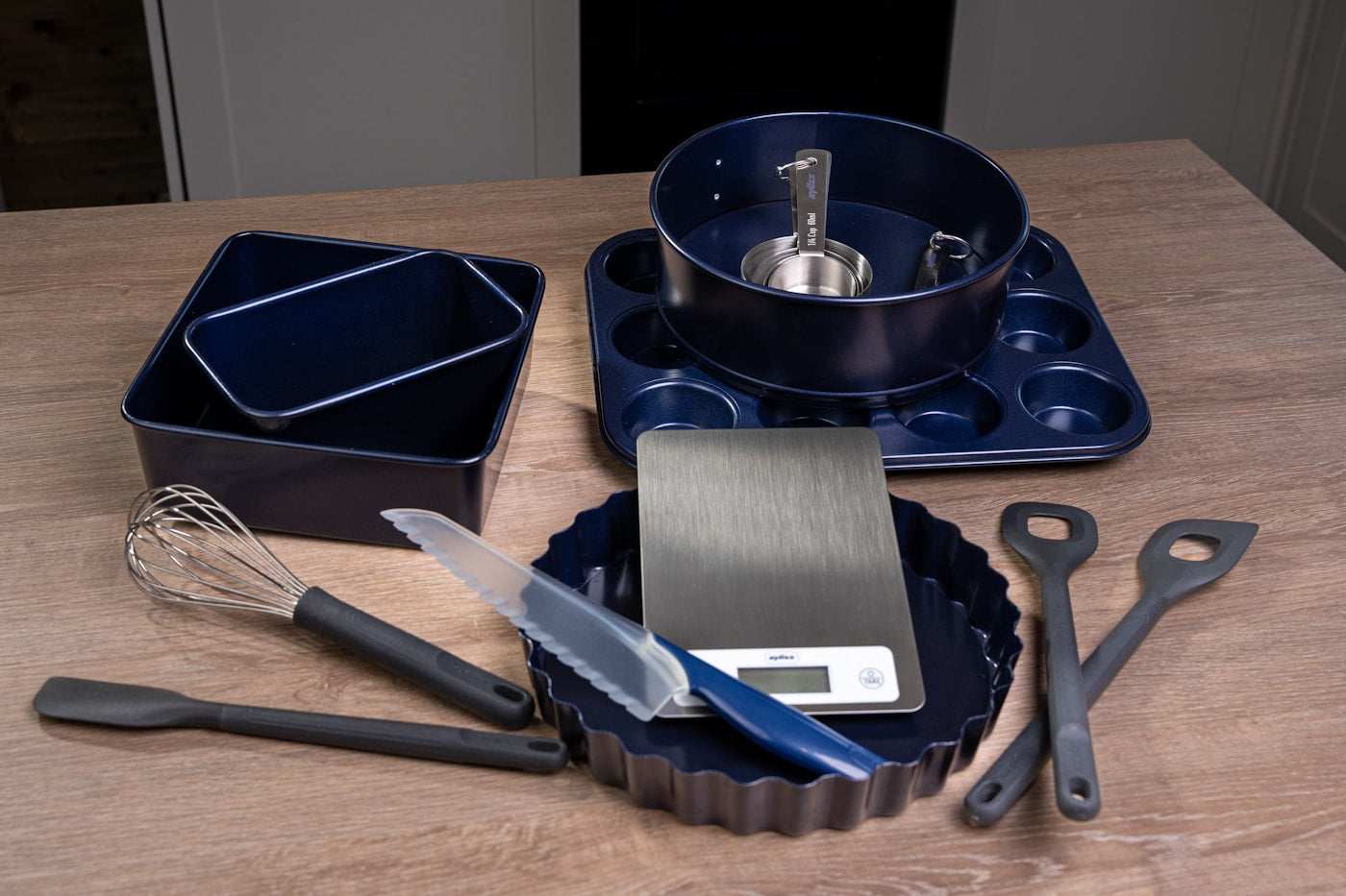 Non-stick pan and kitchen utensils arranged on a wooden table