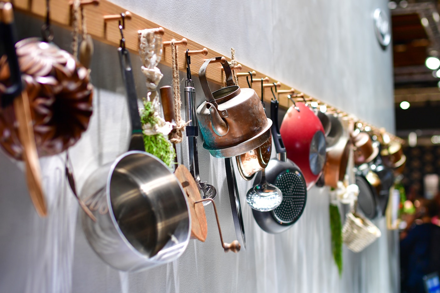 Rustic kitchen utensils and cookware displayed on a wooden rack